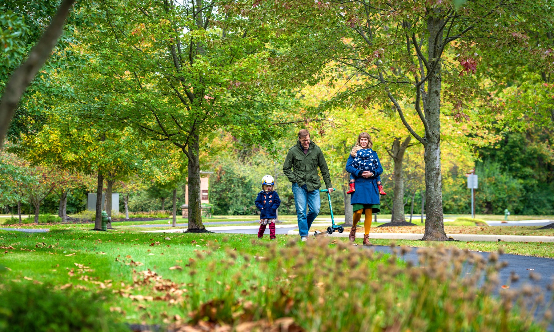 family walking on a path surrounded by trees and lush nature.